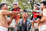 氏子に抱え上げられ元気な泣き声を上げる赤ちゃん力士