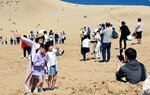 鳥取砂丘と日本海を背景に旅行の思い出を撮影する観光客ら＝３日、鳥取市の鳥取砂丘