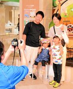 記念号外の写真を撮る家族連れ＝１７日、鳥取市西町３丁目のわらべ館