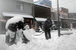 水木しげるロードで雪かきをする店舗関係者＝24日10時22分、境港市松ケ枝町