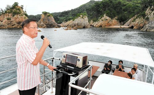 浦富海岸の島を巡りながら、歌声を響かせるモニター客（左）＝１４日、岩美町田後付近の浦富海岸