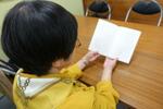 　孫らへの思いを寄せた手記集を手に取る佐々木俊子さん＝１０月、盛岡市