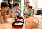 ＡＥＤの使い方を学んでボタンを押す子ども子どもたち