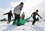 ピッチに積もった雪を運び出すサポーターら＝２９日、米子市安倍のオールガイナーレＹＡＪＩＮフィールド