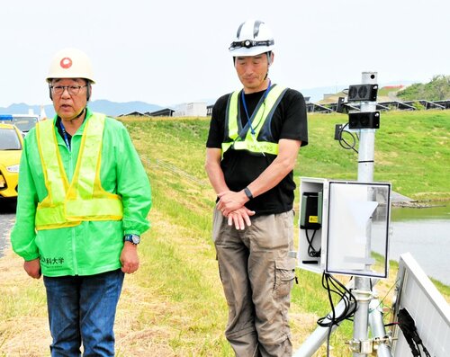 音で鳥を追い払う装置「バードソニック」の効果や運用方法を説明する辻特担教授（左）ら＝２２日、鳥取市の鳥取砂丘コナン空港