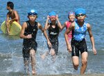 最初の種目となるスイムを終え、残り２種目に向けて走りだす選手ら＝２７日、岩美町大谷の大谷海岸