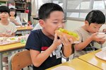  シャインマスカットをパンに挟み、おいしそうに頬張る児童＝１１日、北栄町の大栄小 