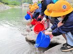 稚アユの成長を願いながら放流する児童ら＝１日、香美町村岡区川会の矢田川