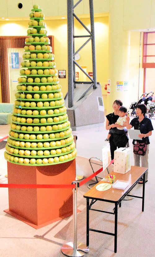 高く積み上げられた梨タワーを見上げる来館者