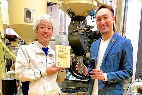 日南町から贈られた木製の感謝状を掲げる萩原社長（左）
