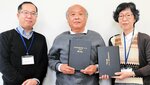 奥館長（右）に「竹村好博著作集」第１巻を寄贈する本上さん（中央）＝２４日、豊岡市京町の豊岡市立図書館
