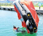 転覆した膨張式救命いかだを元に戻す方法を実践する参加者＝２８日、新温泉町芦屋の浜坂漁港