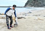 砂浜に流れ着いた流木などを拾い集める参加者＝１８日、新温泉町の居組県民サンビーチ
