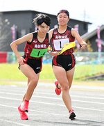女子　鳥取城北は１区河本（右）が２区林に１位でたすきを渡し、序盤から首位を独走する＝竜ケ山陸上競技場