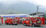 　岡山市南区の山林火災現場付近に集まった消防車＝２４日午前７時３１分