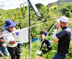 果樹園に設置された装置の設定を確認する辻教授（左端）