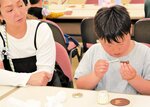 牛革を使ったコースターとストラップ作りに挑戦する親子＝２０日、新温泉町丹土の県立但馬牧場公園