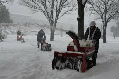 歩道に積もった雪を除雪する作業員＝24日午後1時20分ごろ、鳥取駅南口付近