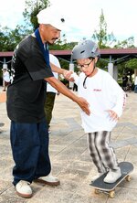スタッフに手を引かれながら滑走に挑戦する児童（右）＝１５日、倉吉パークスクエアふれあい広場