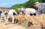 力を合わせて大綱を編んでいく住民ら＝１日、新温泉町湯の温泉小グラウンド