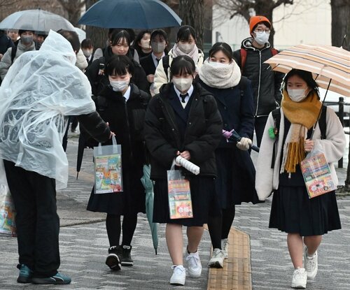 傘を差して会場入りする受験生＝１３日、鳥取市の鳥取大