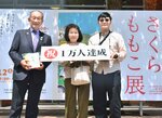 来場者１万人目の記念品を受け取ったなおみさん（中央）と史隆さん（右）＝２日、米子市美術館