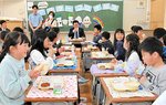 伊木市長（正面奥）とアフターコロナを記念した給食を対面形式で味わう児童ら＝８日、米子市旗ケ崎５丁目の住吉小