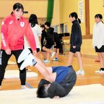 児童にマット運動を指導する三上さん（左）