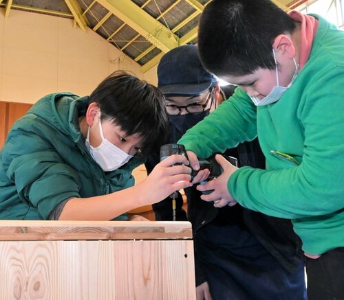 電動ドライバーを使って本棚を組み立てる児童ら