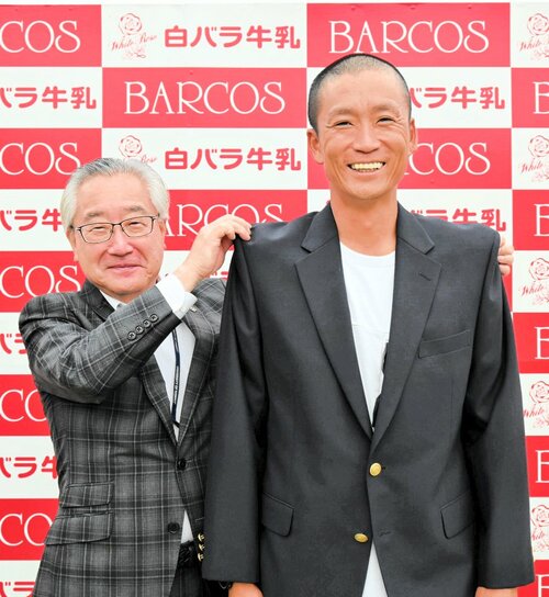 吉岡社長（左）からチャンピオンブレザーを贈られた奥村監督＝１日、倉吉市営陸上競技場