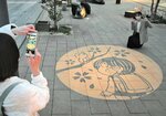 写真を撮って春をテーマにした限定影絵を楽しむ観光客＝９日、境港市大正町