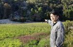 　土砂が流入した田んぼを指さす川原伸章さん＝石川県輪島市