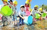 「大きくなってね」と稚アユを放す園児ら＝１７日、米子市八幡