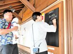 パネル横に設けられた黒板に記載する上村さん夫妻＝１２日、新温泉町湯の夢小路