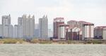 　北朝鮮北西部新義州周辺に新たに建てられた高層住宅（右側）と中国遼寧省丹東の高層ビル街＝１４日（共同）