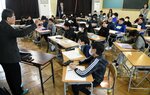 玉栄丸爆発事故について根平さん（左）の説明を聞く児童ら＝１４日、境港市湊町の境小