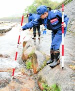 ポールを使って川底に異常がないかを確認する国交省倉吉河川国道事務所の職員＝２３日、倉吉市関金町関金宿の滝川親水公園