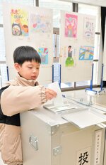記入した投票用紙を投票箱に入れる児童