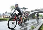 雨の中、懸命にペダルを漕ぐ参加者ら＝２３日、湯梨浜町の中国庭園燕趙園周辺