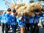 わらで作った大蛇を担ぎ、かけ声とともに集落を練り歩く住民ら＝１０日、大山町赤松