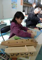 青谷上寺地遺跡から出土した弥生時代の琴のペーパークラフトを作る参加者＝２３日、鳥取市青谷町露谷の青谷町体育館