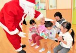 サンタクロース（左）からうれしそうにプレゼントを受け取る園児たち＝２５日、香美町村岡区村岡の宝樹保育園