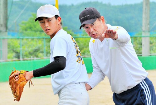 丁寧に投球動作を指導する川口さん（右）＝２１日、八頭高グラウンド