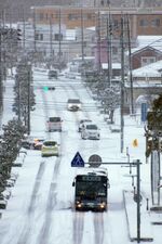 雪が積もった道路をゆっくりと走行する車＝24日午前７時43分、境港市上道町