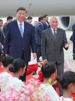 　１７日、カンボジア・プノンペンの空港で出迎えを受ける中国の習近平国家主席（左）（カンボジア政府提供、共同）