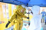 防護服を着て除染作業の流れを確認する参加者ら＝７日、三朝町総合スポーツセンター
