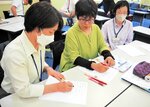 手書きの要約筆記で講演などの内容を伝える要約筆記者（左）