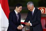 　２０２４年５月１５日、シンガポールのウォン新首相（左）と握手するリー・シェンロン氏（ロイター＝共同）
