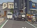 　埼玉県三郷市の市道で、小学生らの脇に止まった車（右）＝１４日（住民提供）
