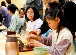 茶せんの動かし方を教わりながら茶をたてる子どもたち＝２８日、鳥取市掛出町の市民会館